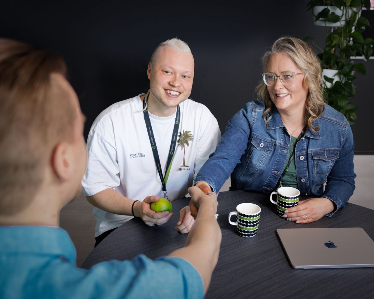 two people greeting a third person with a handshake