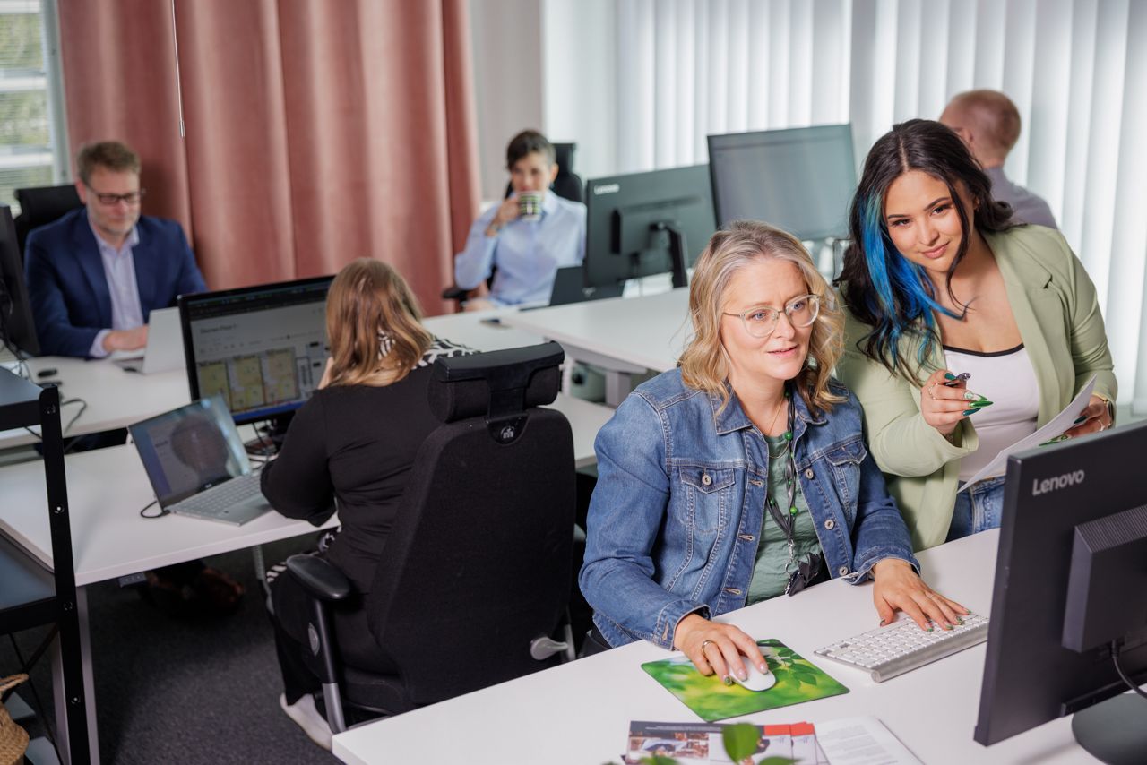 9Solutions employees watching a desktop monitor and smiling