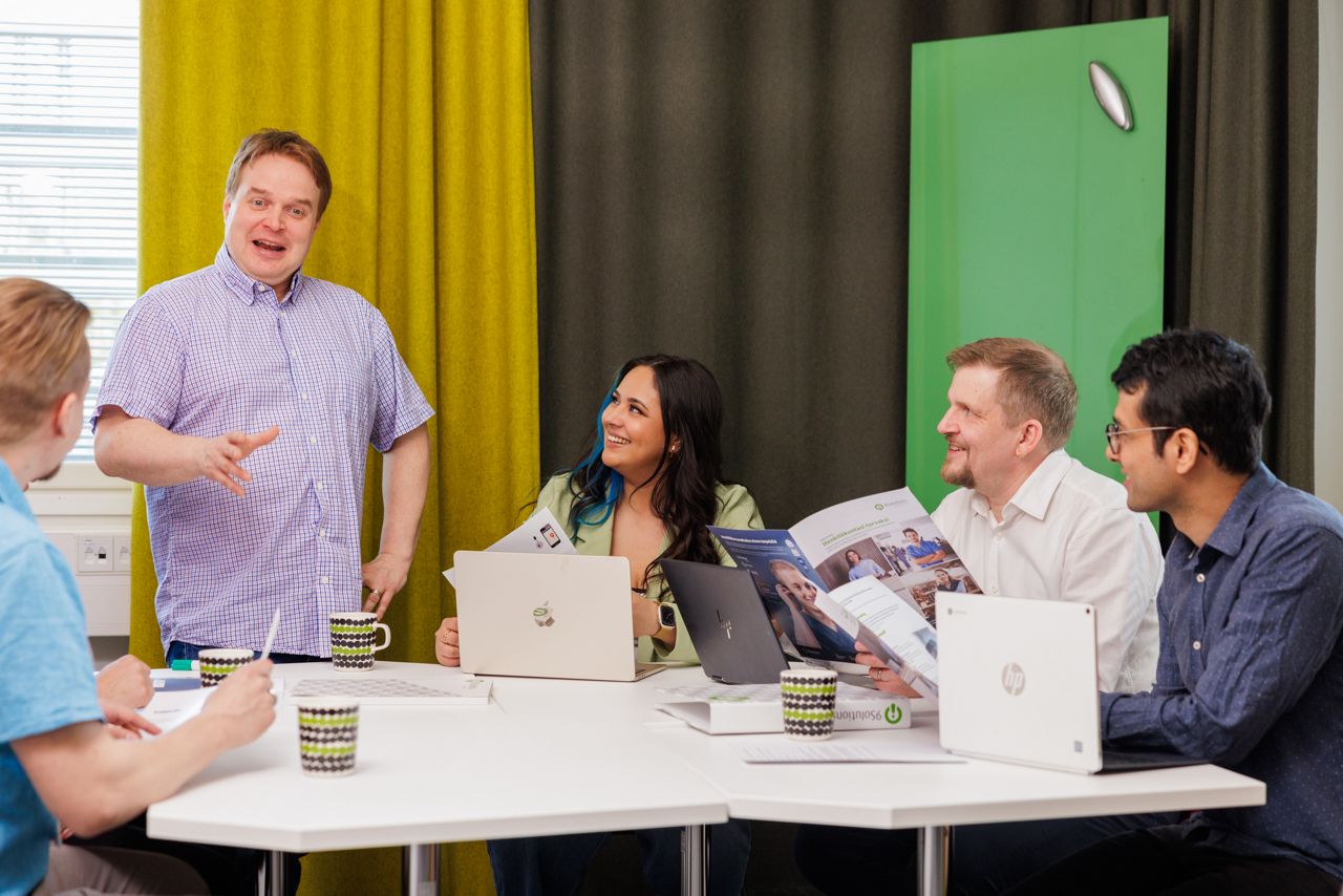 five people laughing in a meeting room