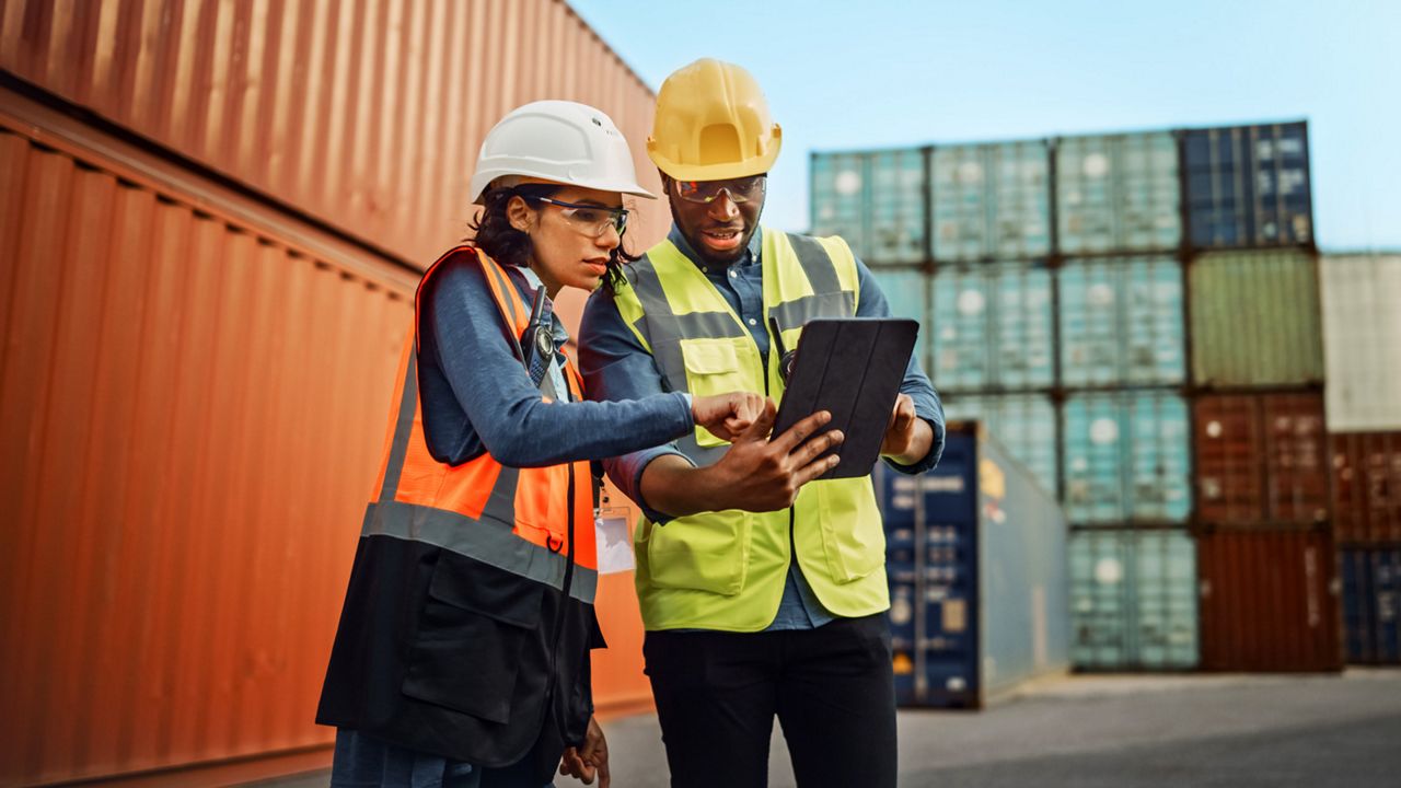 A couple of employees using the tablet at the port