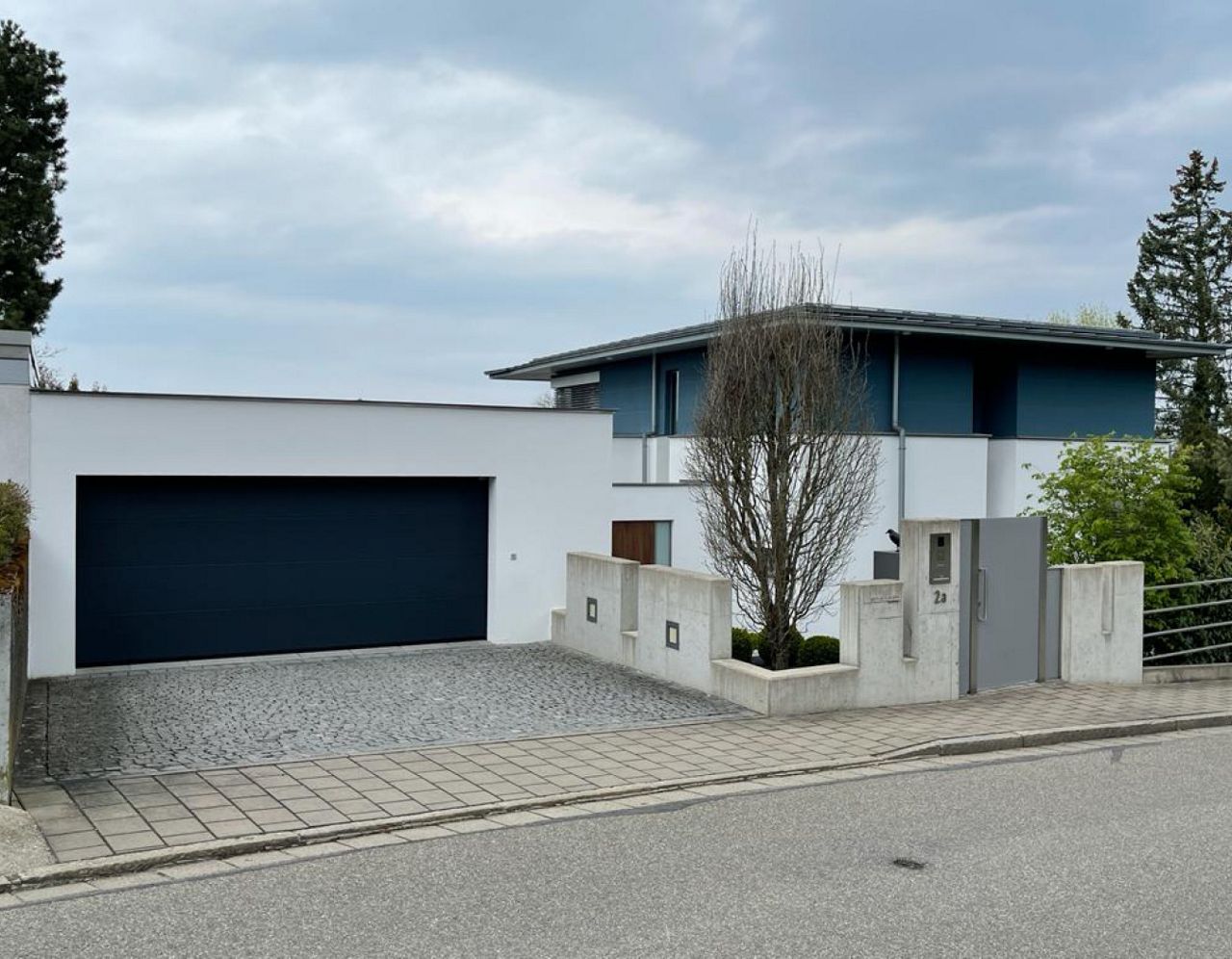 Elegantes Normstahl-Sektionaltor für die Garage, installiert an einem modernen Haus, mit klarem Design und eleganter Verarbeitung.