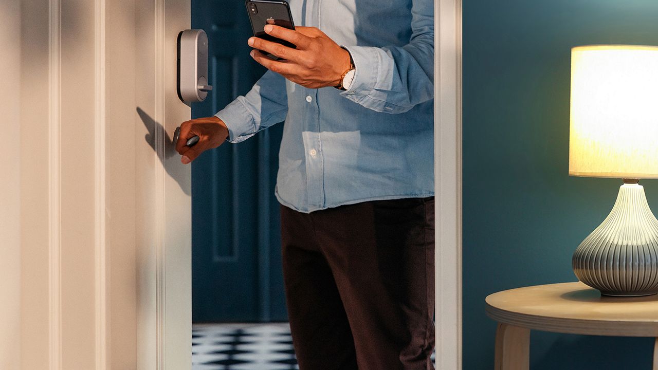 En mann går ut inngangsdøren med en telefon i hånden.