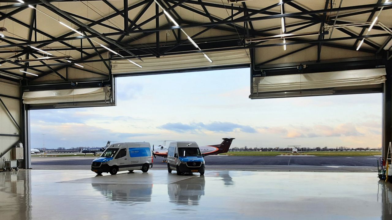 Servicevrouw haalt iets uit de witte ASSA ABLOY vrachtwagen. 