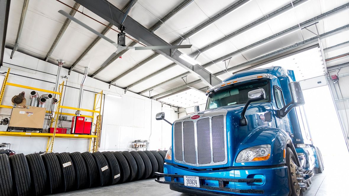 Image: A Black 3 Blade HVLS Fan in a garage with a semi truck.