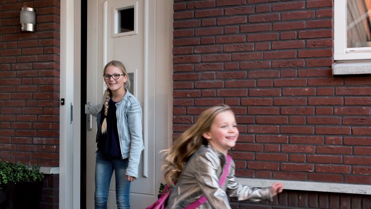 Kinderen lopen naar buiten bij een woning met open voordeur