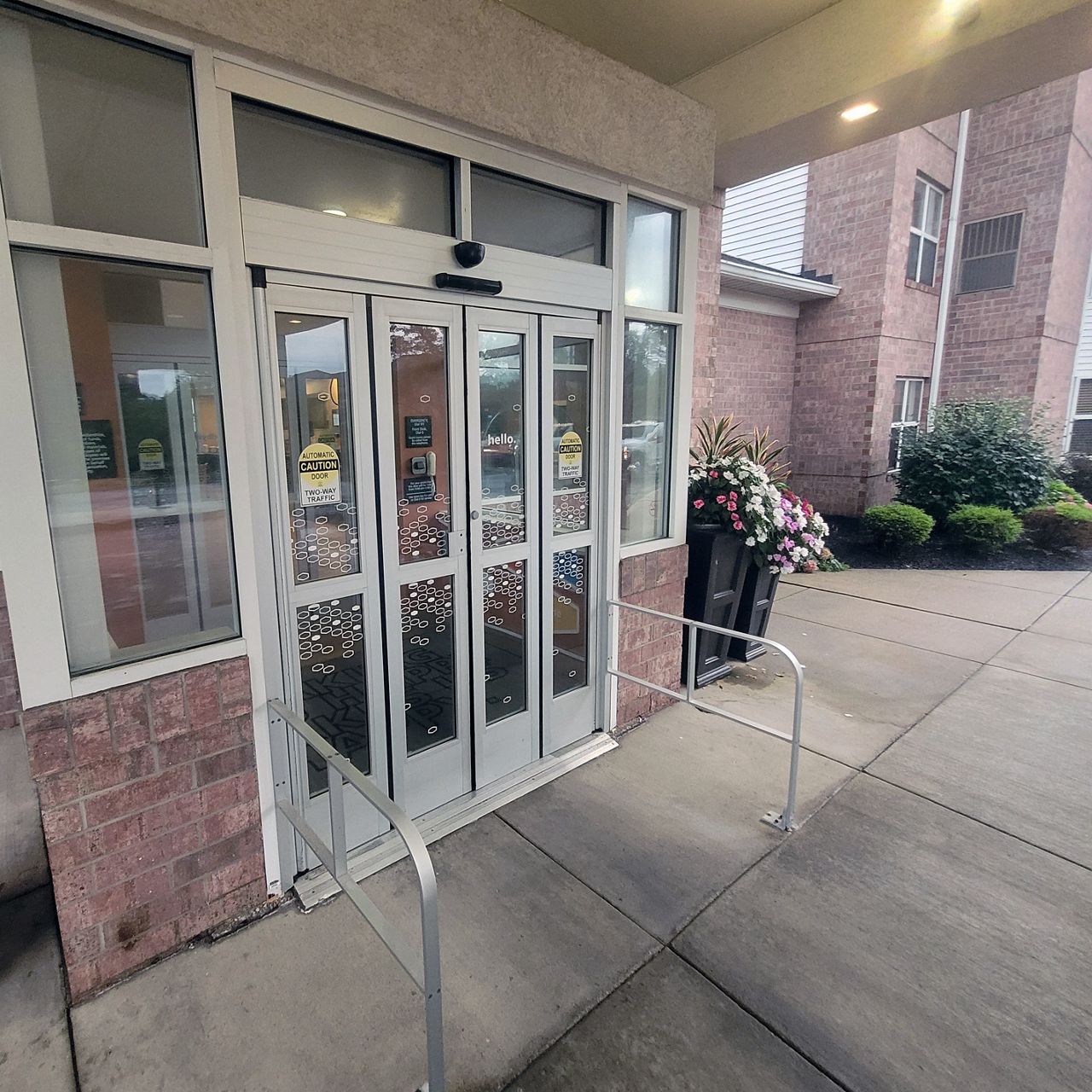 Image shows a closed aluminum door on the entrance to a hotel with four narrow panels that fold and slide open. 