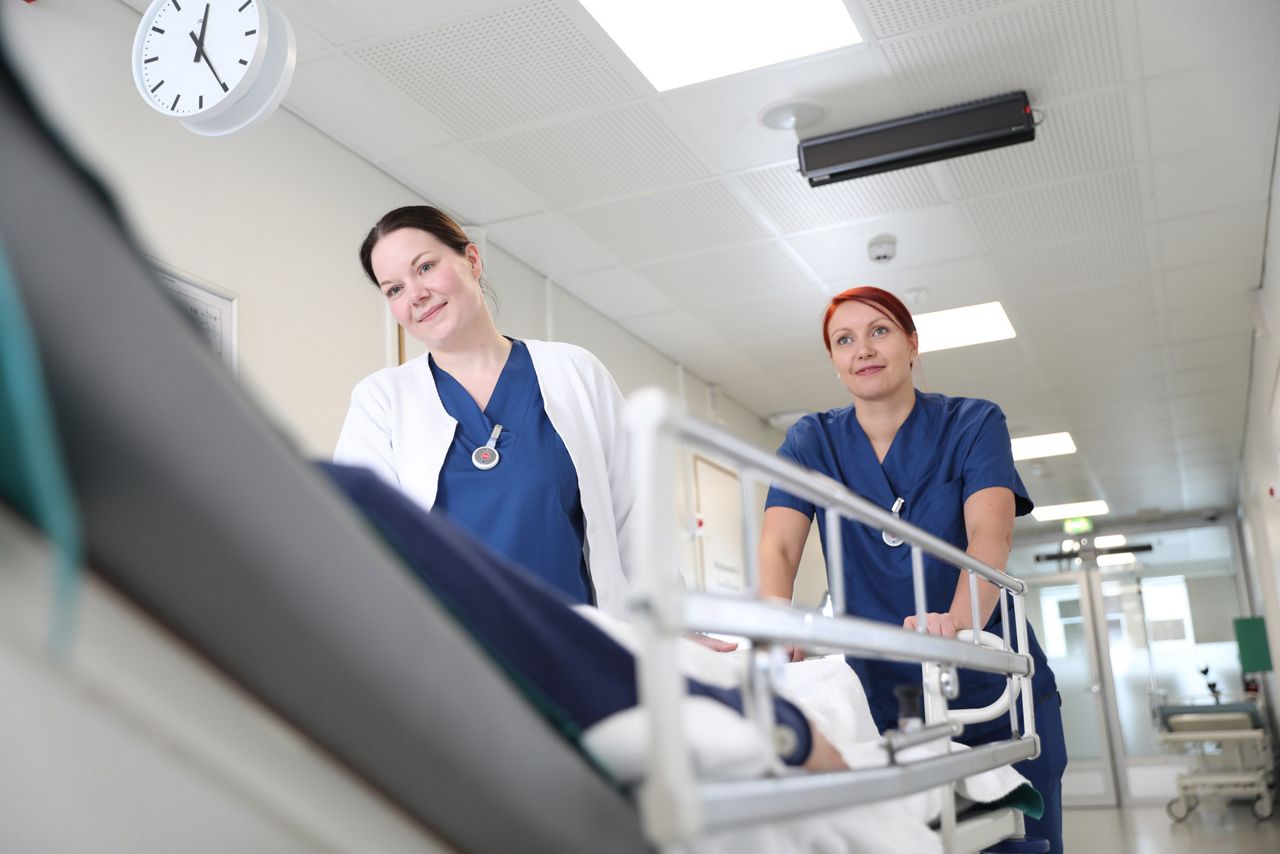 Two nurses pushing hospital bed wearing 9solutions product