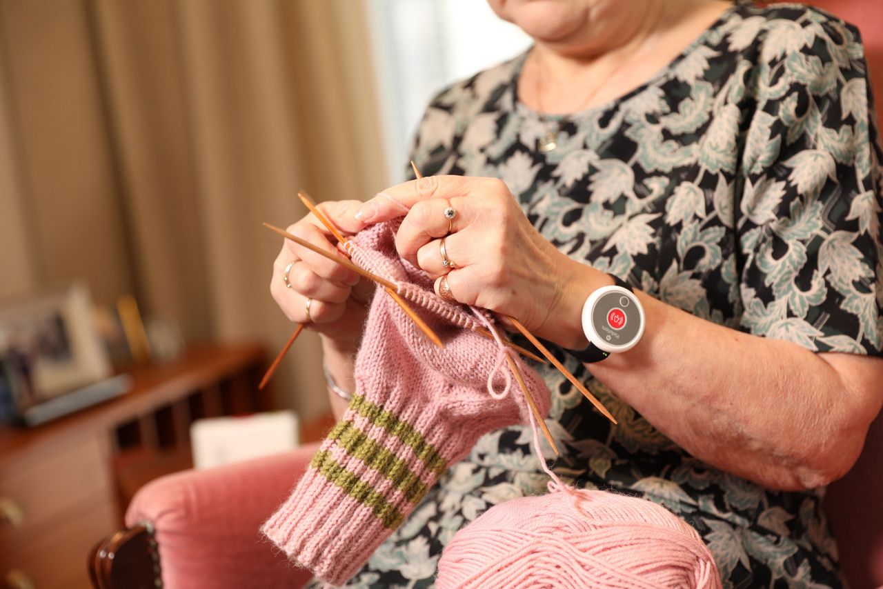 old woman wearing a safety tag knitting