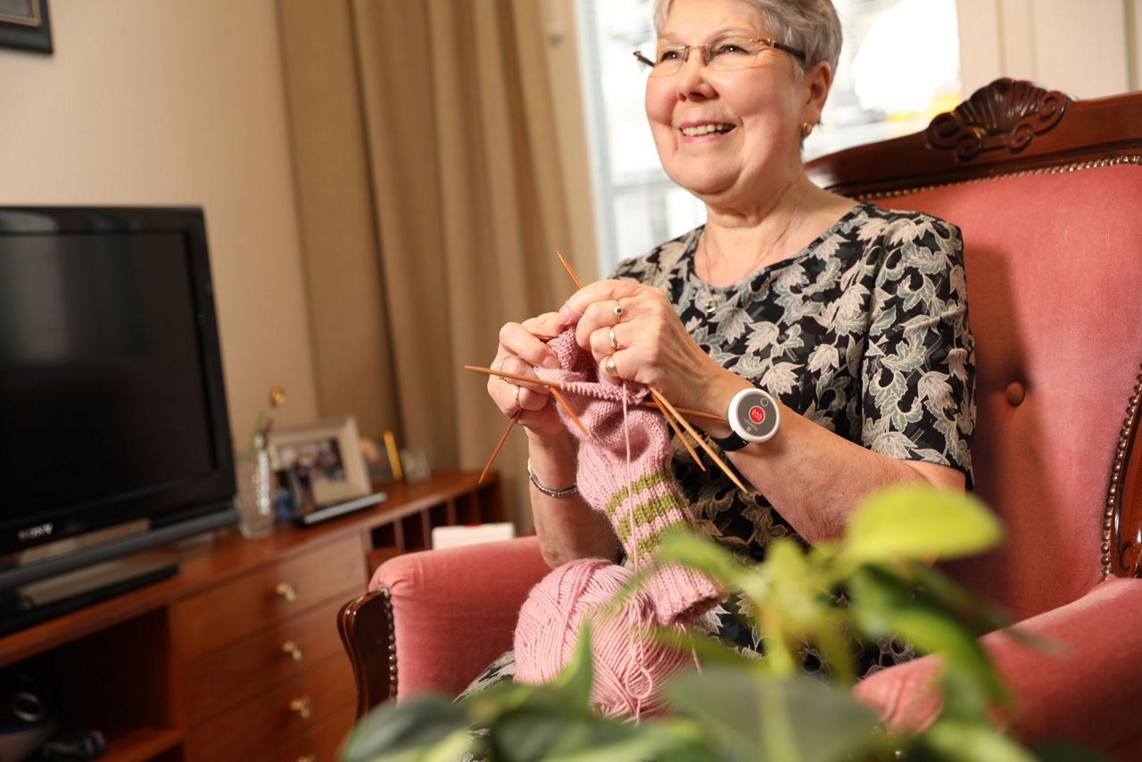 Old woman knitting a sock wearing a 9solutions safety tag