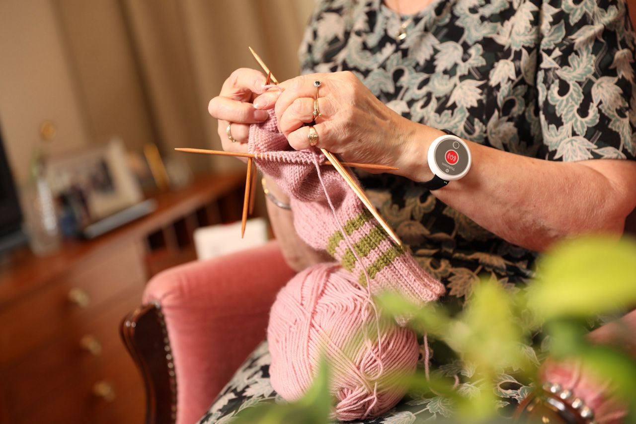 Old woman wearing a safety tag and knitting