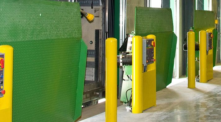 A line of 3 green dock levelers in a warehouse