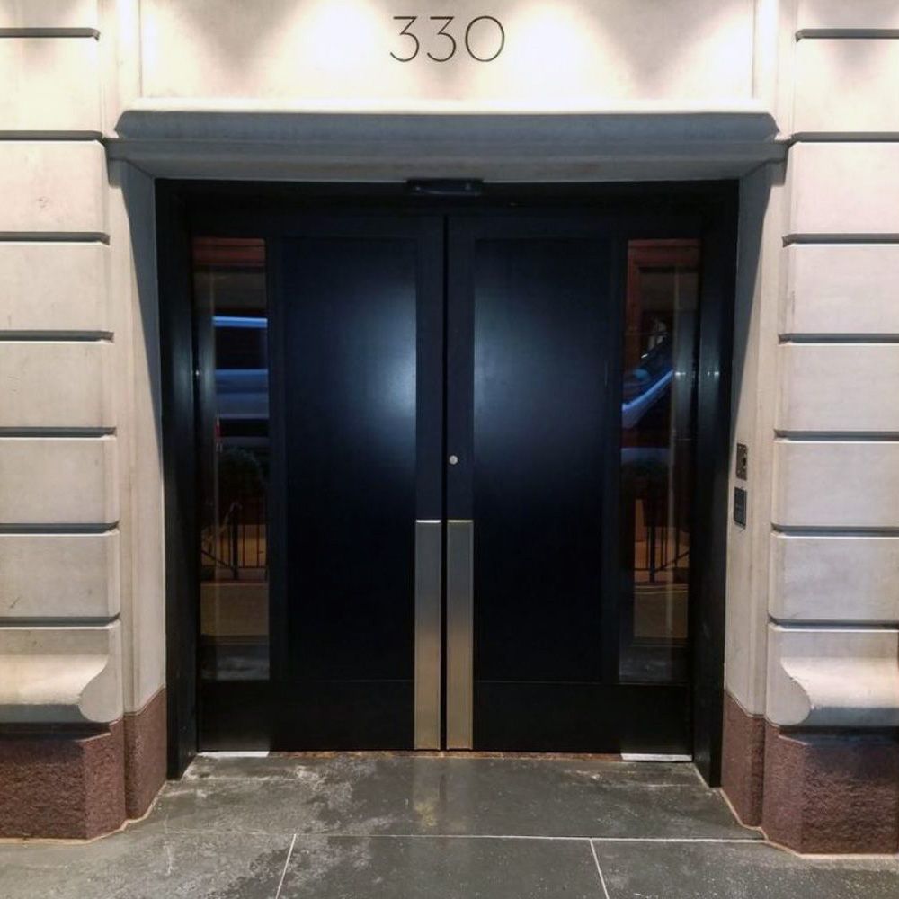 A dark wooden door on a New York City hotel entrance.
