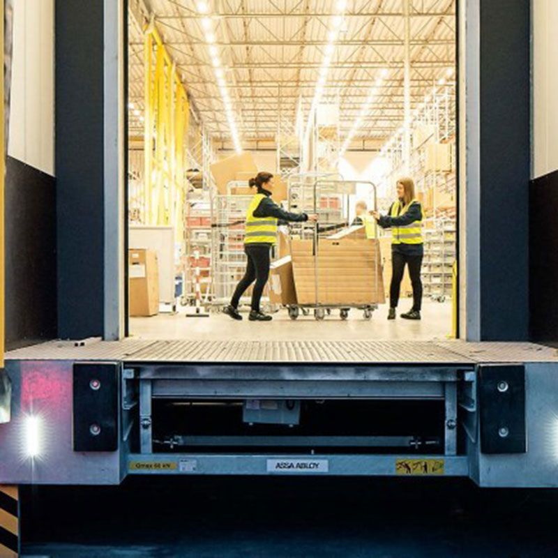Two people with parcels at a loading dock.