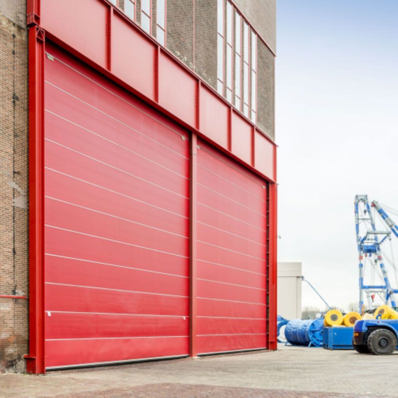 A brick building with red Megadoors in an industrial environment.