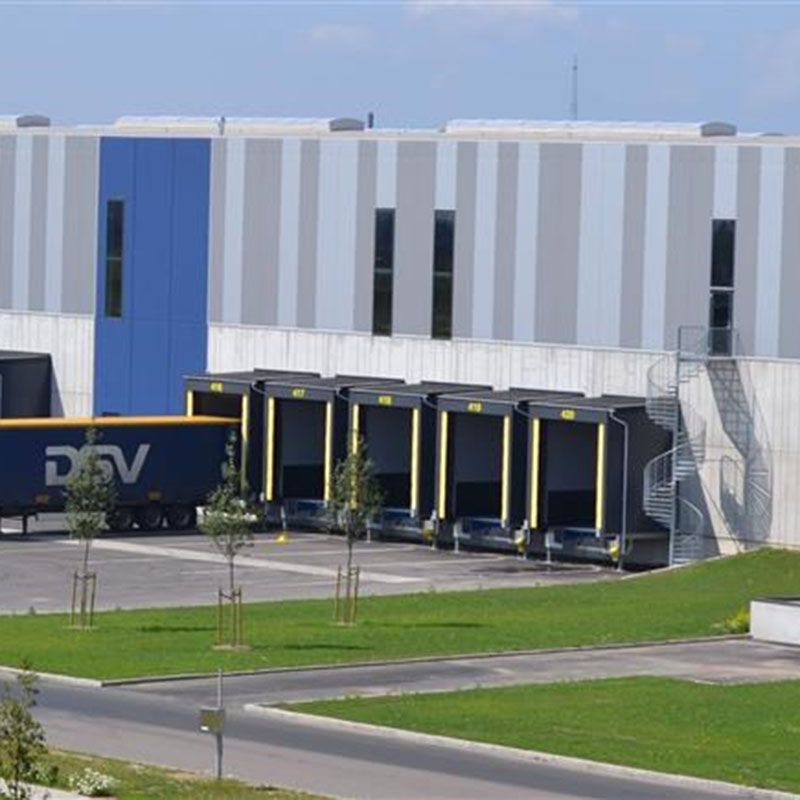 Loading docks with trailer at the DSV facilities. A big grey building with grey and yellow doors.