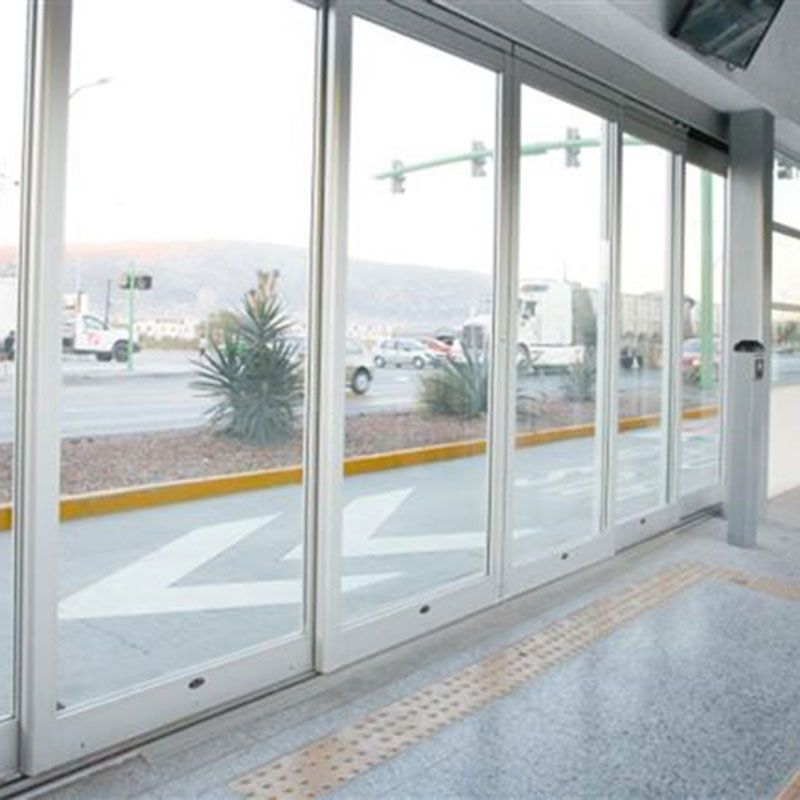 Hala za tranzit s sistemi avtomatskih vrat v sistemu Ecovía BRT. Velika steklena okna in vrata. Zunaj lahko vidite majhne palme in pločnik.