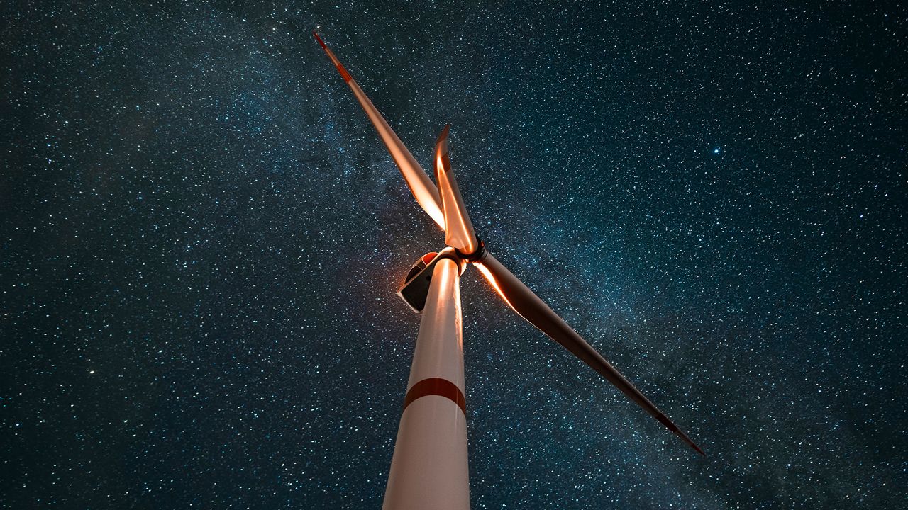 Une éolienne avec un ciel étoilé en arrière-plan.