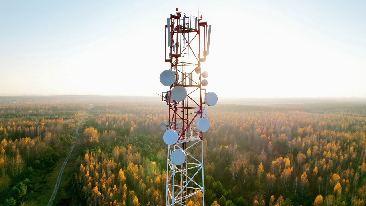 A telecom tower with trees in fall colors in the background.