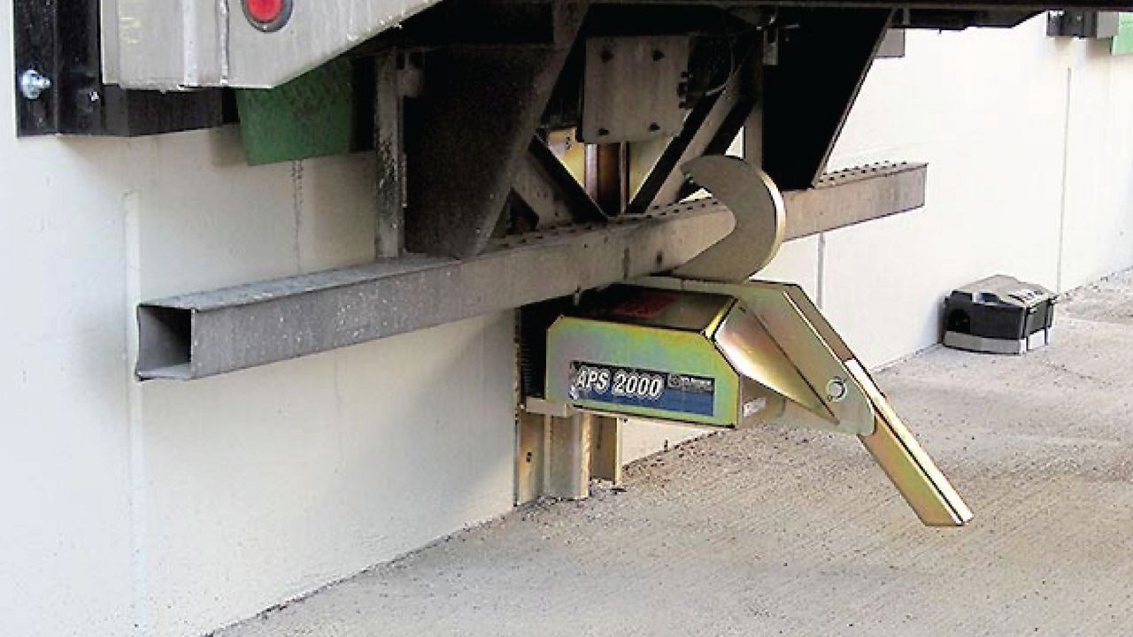 Left view of a heavy-duty industrial device featuring a versatile restraining arm and durable construction for enhanced vehicle security.