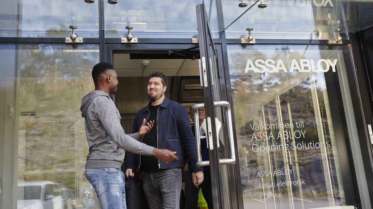 To kolleger som står utenfor inngangen til ASSA ABLOY.