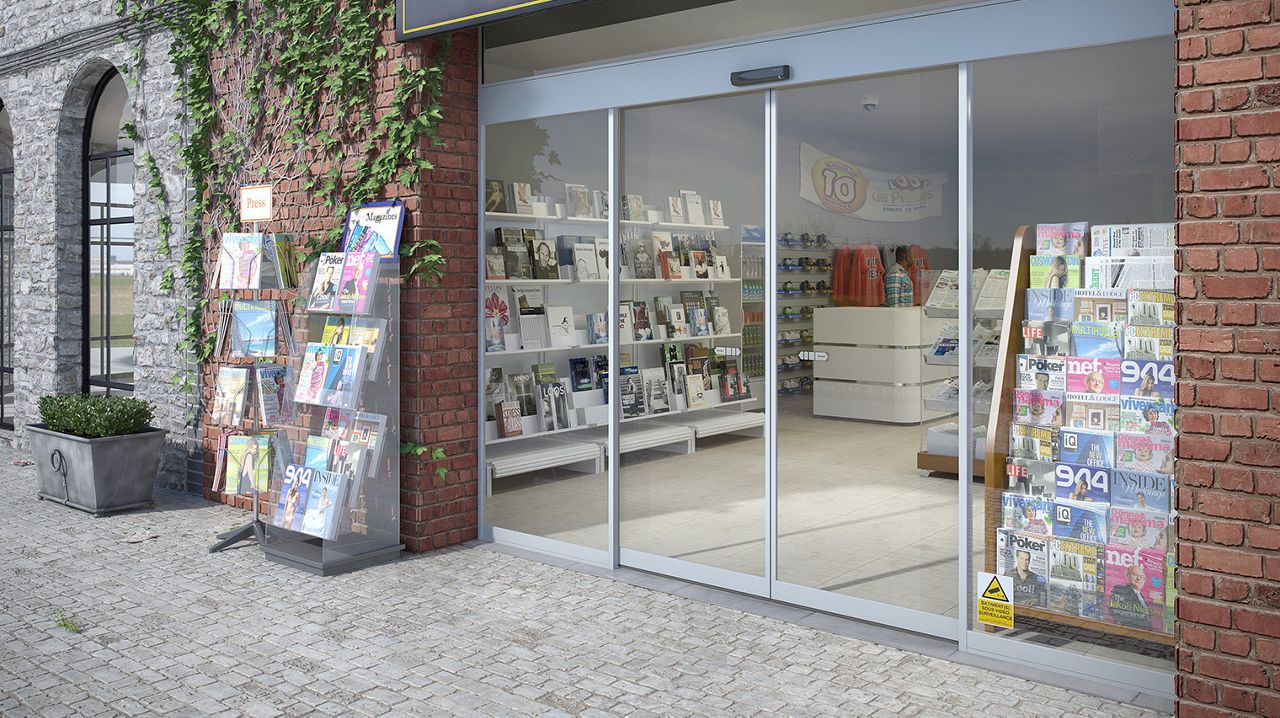 Vista frontal de una tienda de periódicos con las puertas correderas SL500 S Slim de ASSA ABLOY.