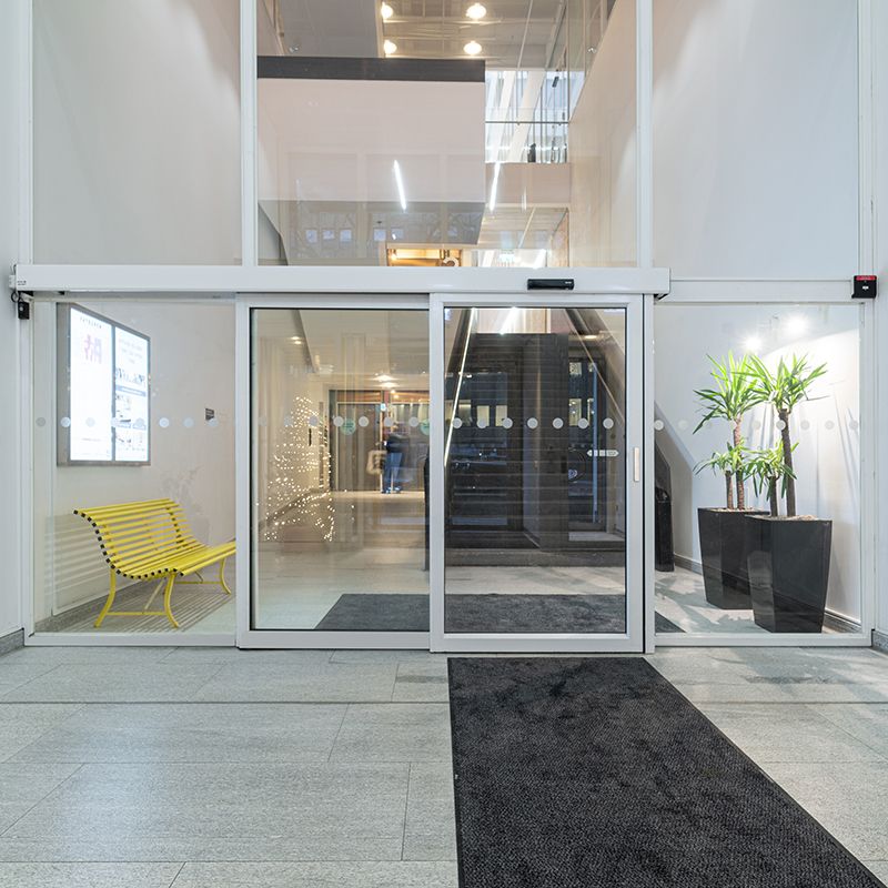 Glass sliding doors with the ASSA ABLOY SL521 telescopic sliding door operator in a bright public facility.