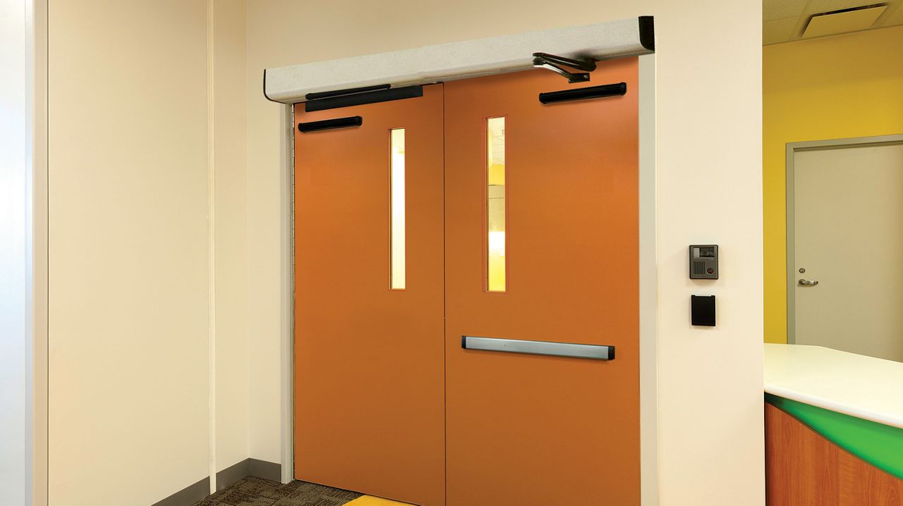 Portes orange avec l’opérateur de portes battantes ASSA ABLOY SW200i dans un hôpital.