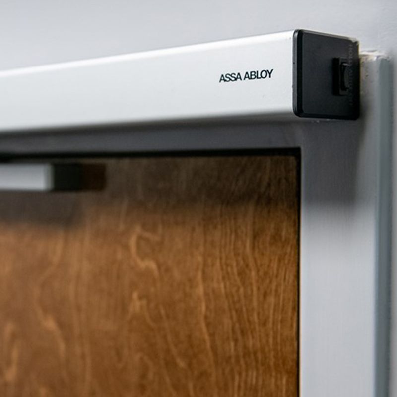 ASSA ABLOY 必盛 SW60 平开门机在棕色木门上的特写镜头。