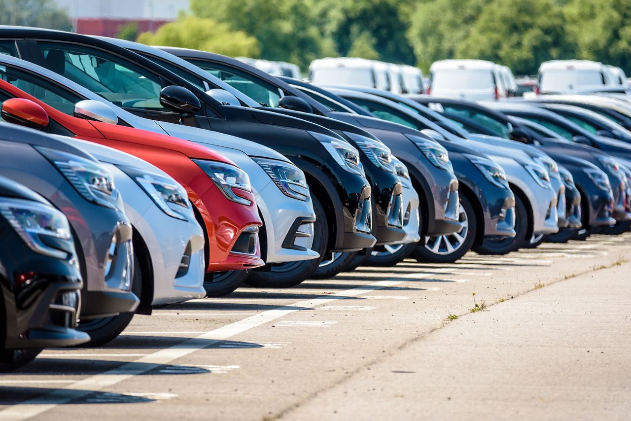 row of cars in a car dealership lot during the day
