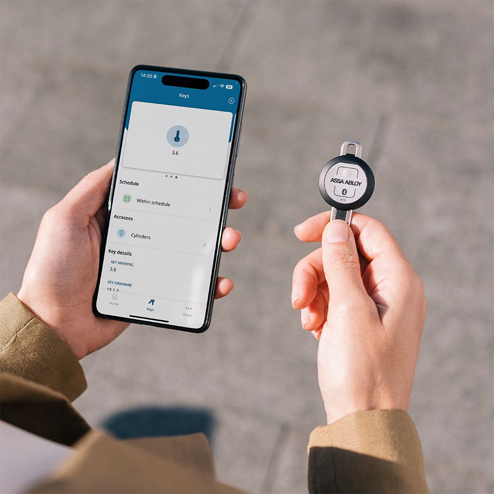 Image: ecran smartphone cu aplicația cliq și o cheie cliq in mainile unei persoane
