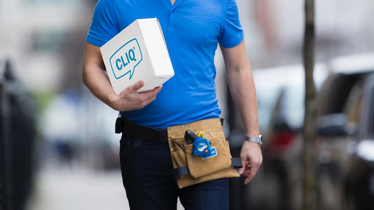 A man walks with a box with ASSA ABLOY's CLIQ logo on it.