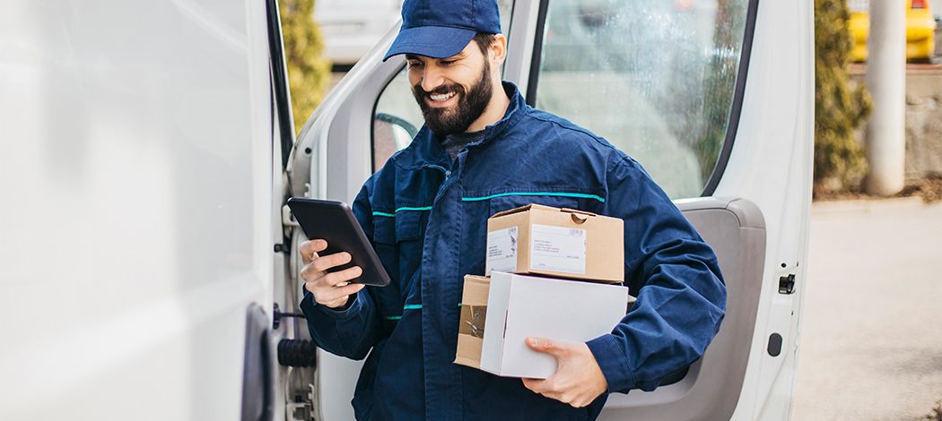 Man carrying parcels while holding mobile phone