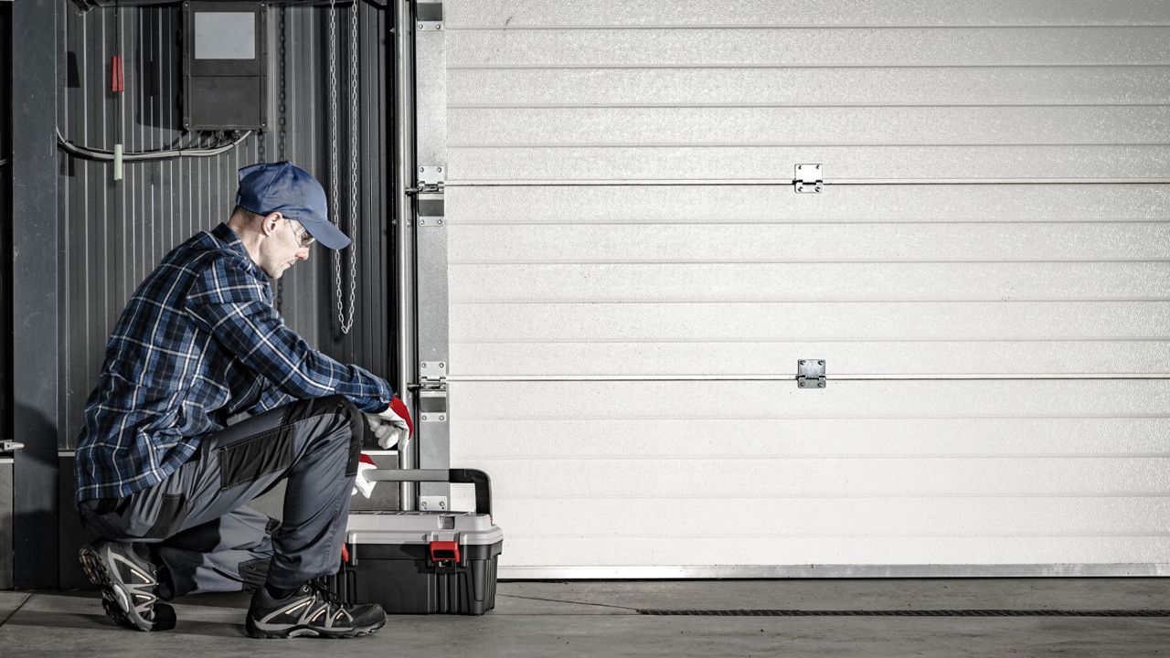 Un professionnel de la fermeture qui intervient sur la pose d'une porte de garage.