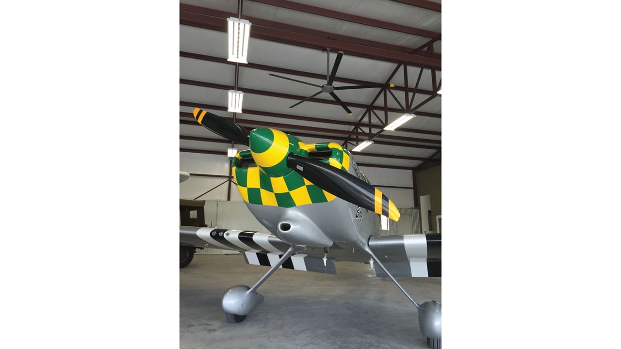 A small, multi colored plane with a silver fan with 5 blades above it