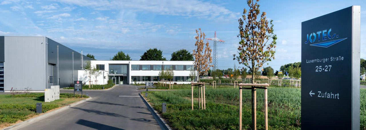 Gebäudeansicht der Firma Jotec mit Einfahrtsschild und Adresse