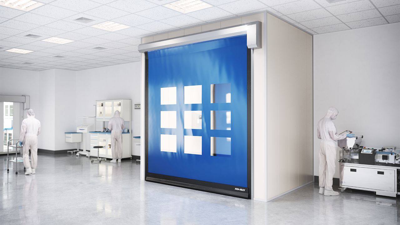 A blue door in a controlled enviroment and workers in white safty garments. 
