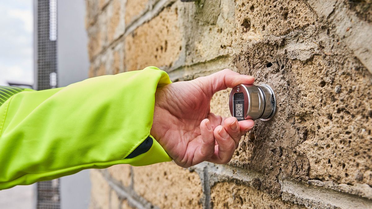 Billede af en hånd, der holder en cylinder, der sidder i en mur