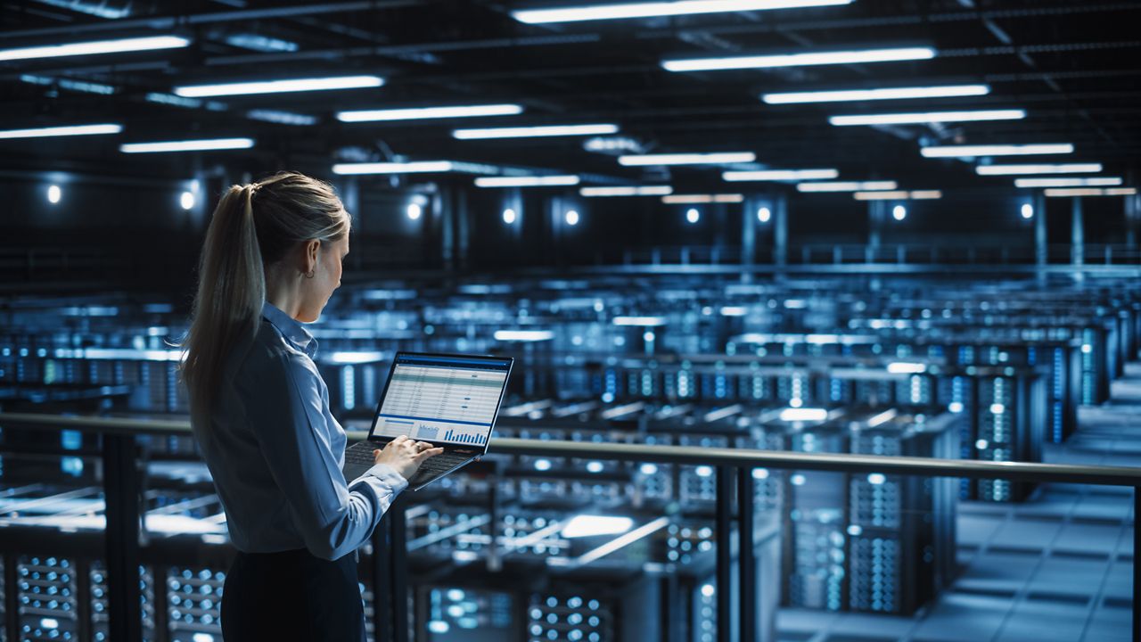 Woman working on laptop overseeing data center operation