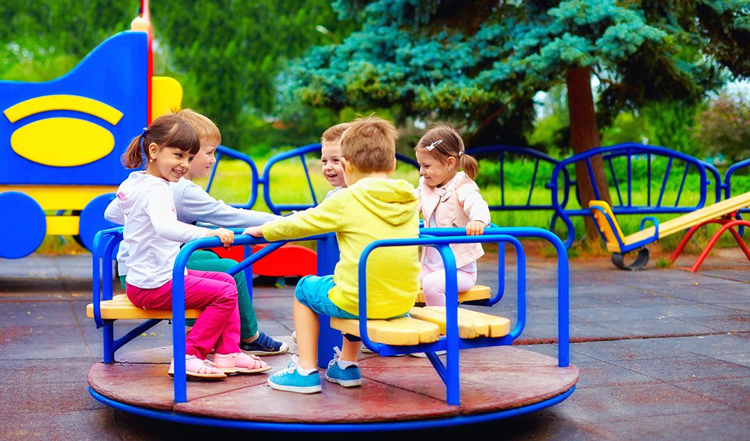 Little kids playing on a merry go round.