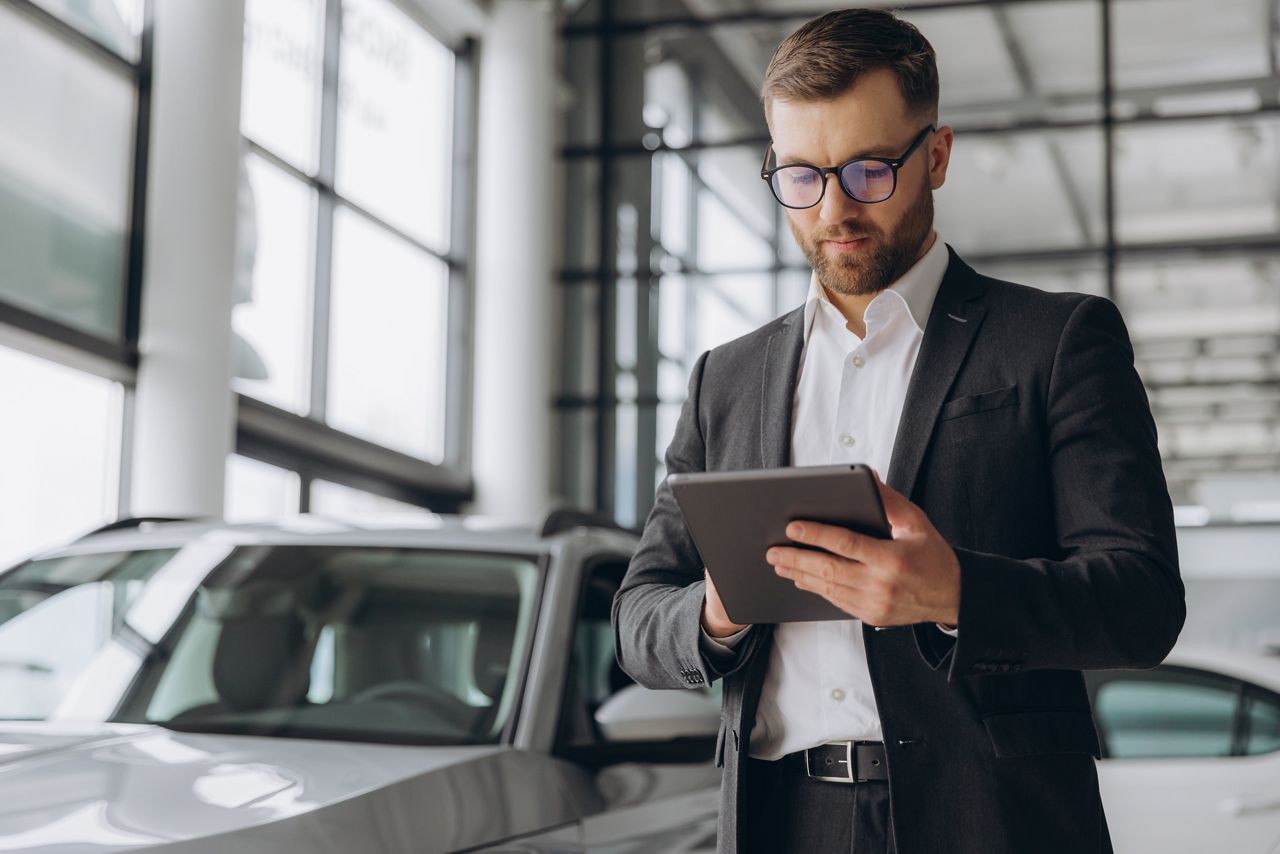 Car dealer looking at a tablet in the showroom
