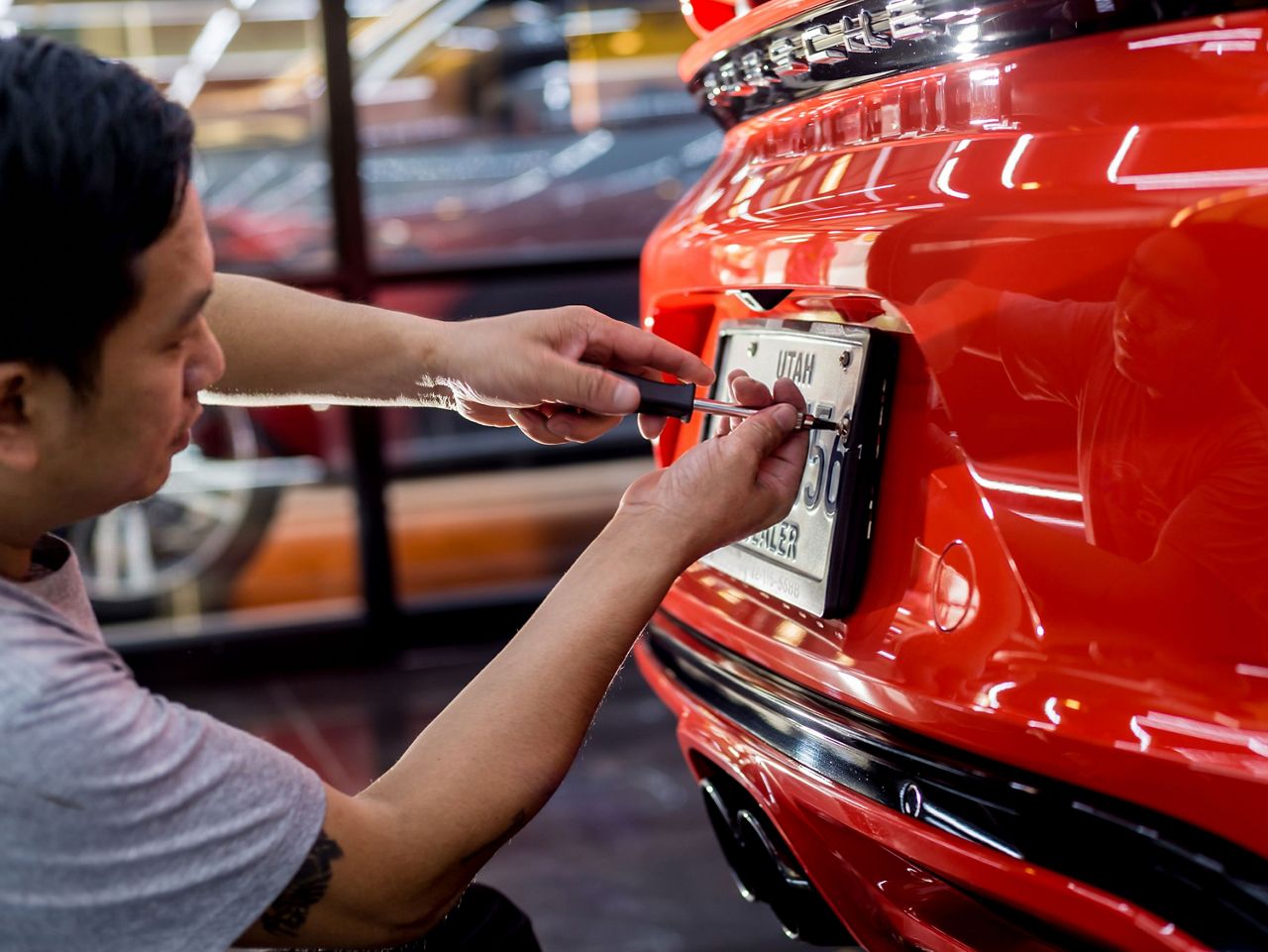 Man installing a dealer plate on a new car