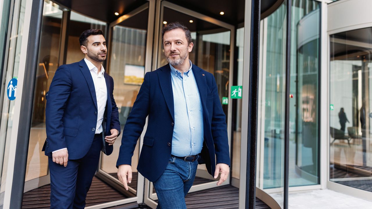 Két férfi halad át forgóajtón