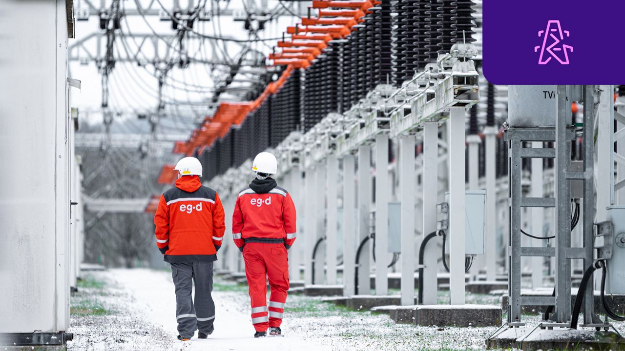 Two workers walking under energy infrastructure