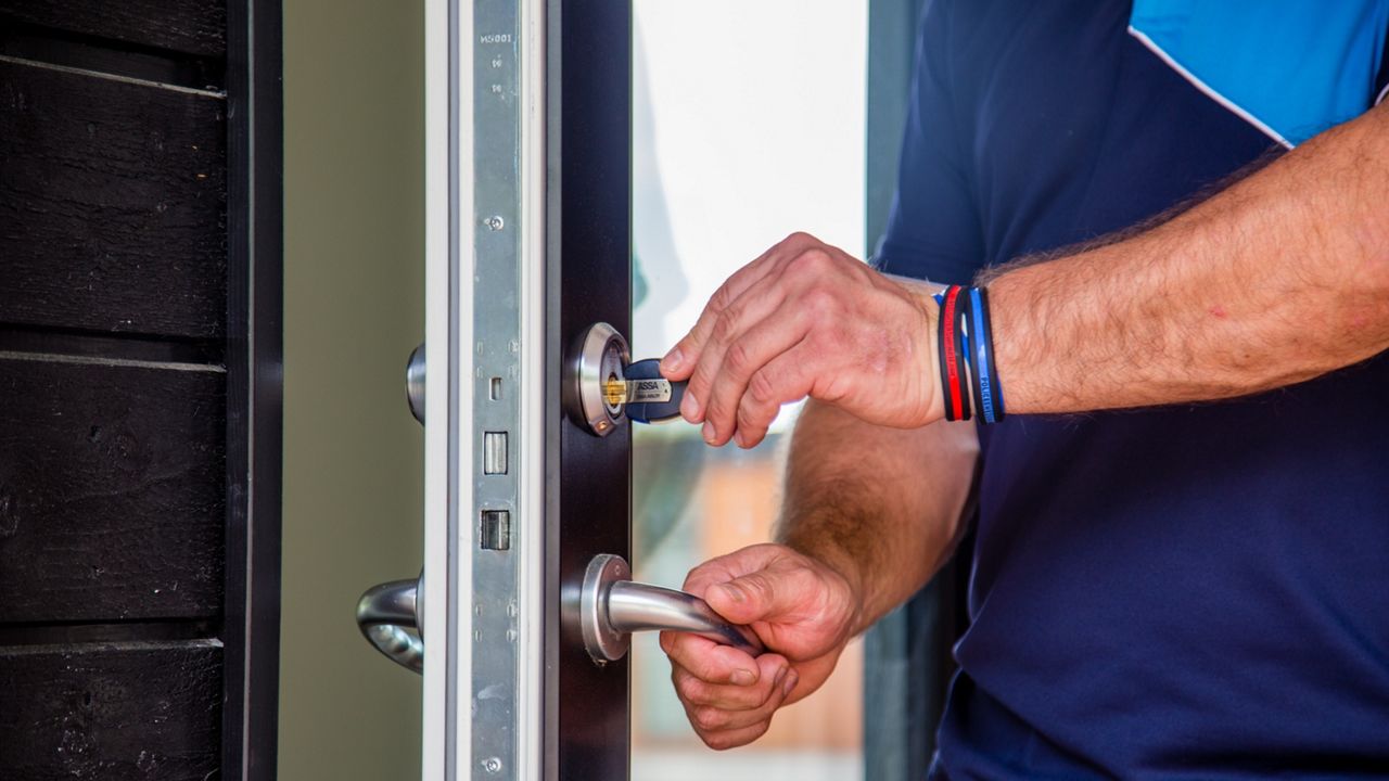 En mann åpner en dør med ASSA ABLOY-lås.