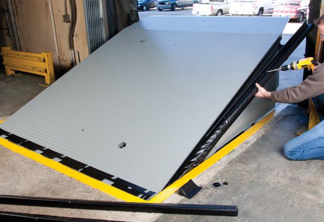 Image: A warehouse worker installing the Energy Guard Dock Leveler Weatherseal at the loading dock.