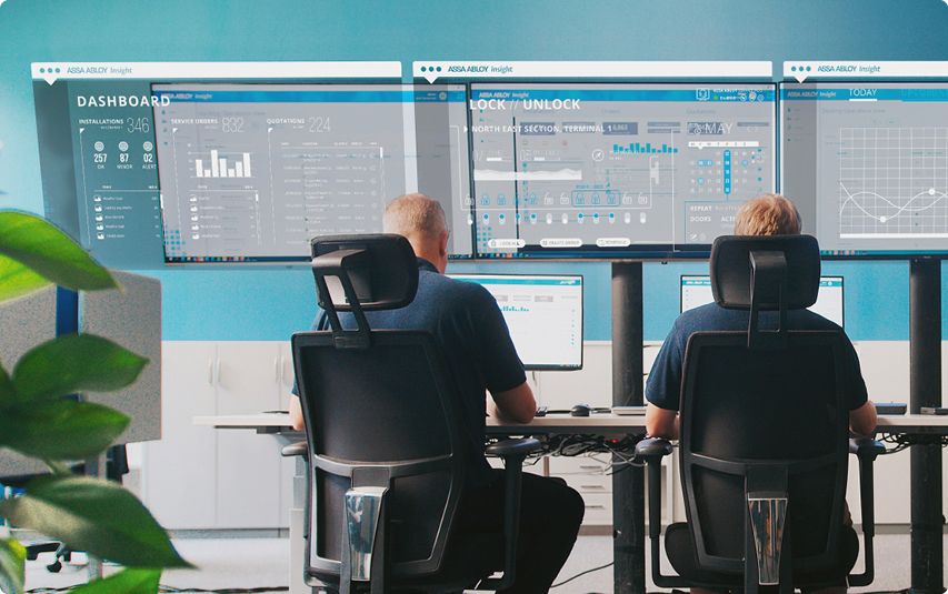Two people sitting infront of several data screens looking at data figures