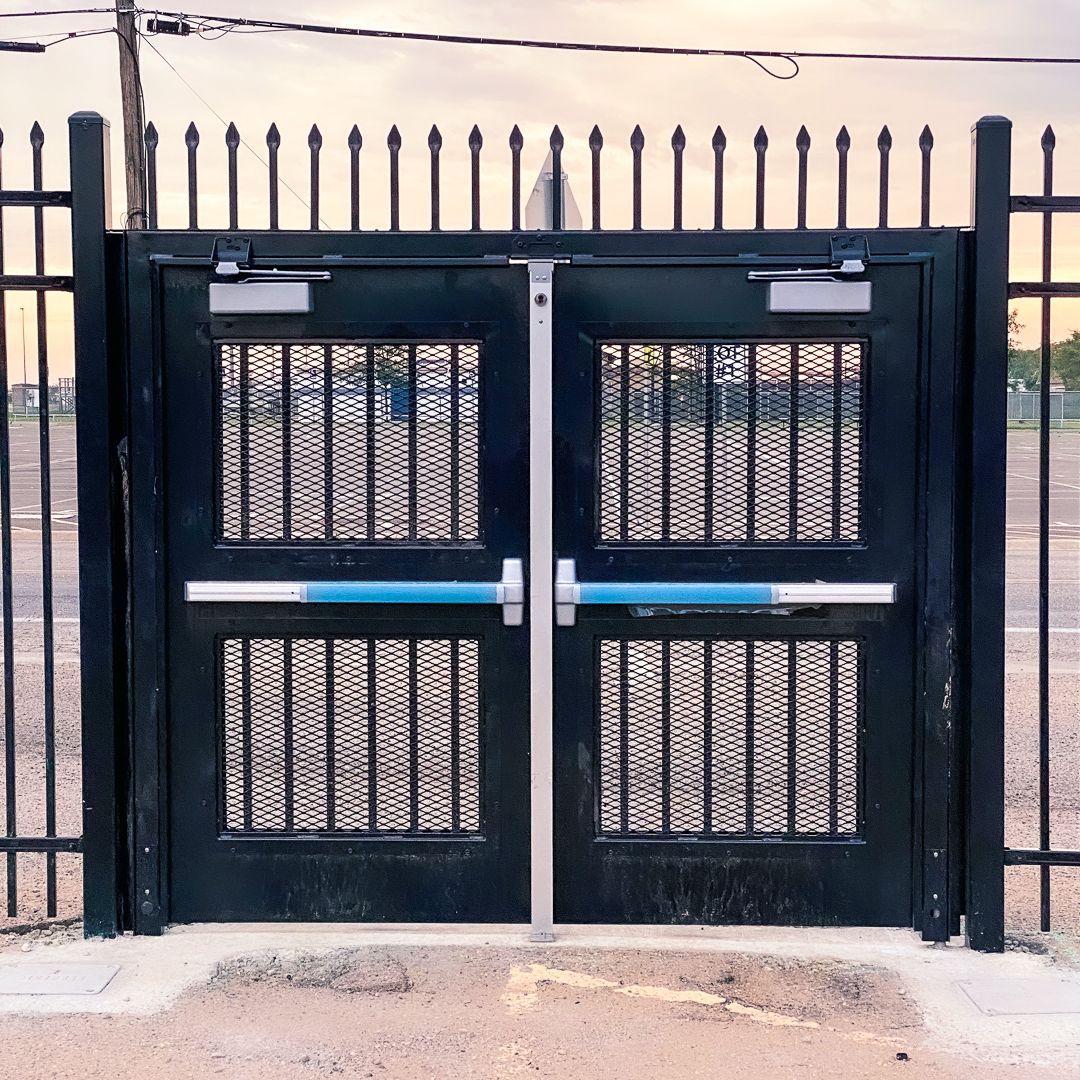 Exodus double swing gate with pickets and infill and panic hardware.