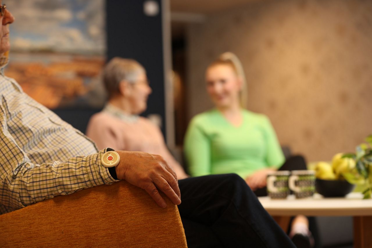 Closeup of a an old man sitting nd wearing a 9solutions safety tag on his wrist