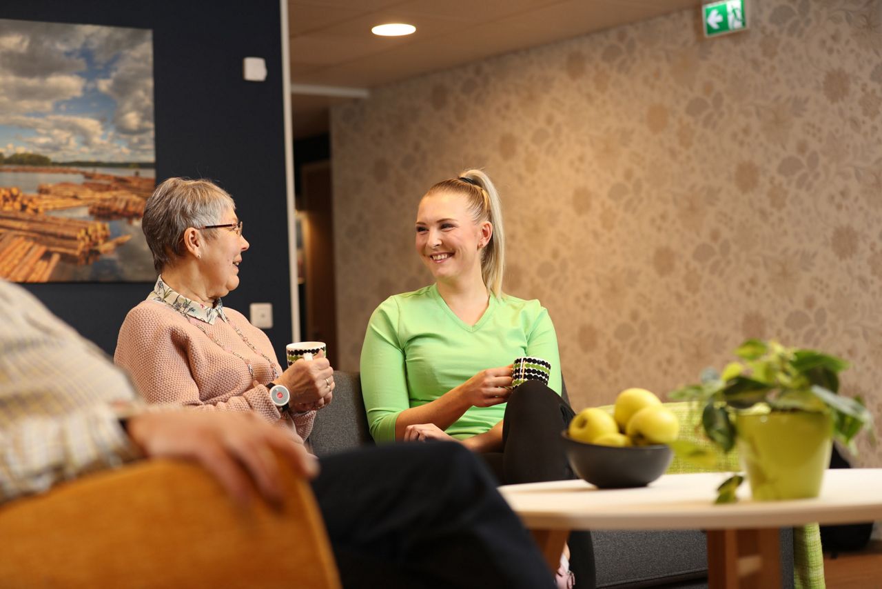 Nurse and a resident having coffee in an care home