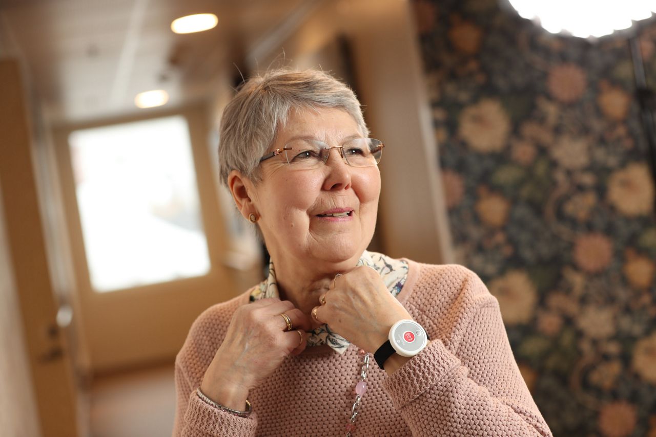 old woman smiling wearing a safety tag